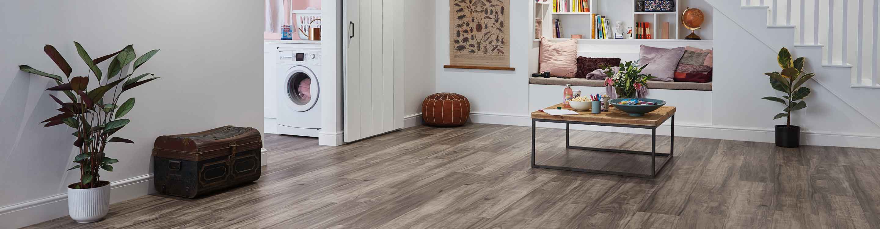 gray plank wood look vinyl in finished basement with reading nook, coffee table, and sliding barn door to laundry space